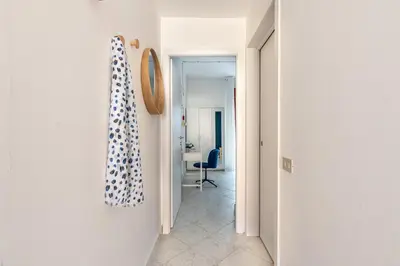 a hallway leading to a room with a blue chair at Ludohome in Palermo