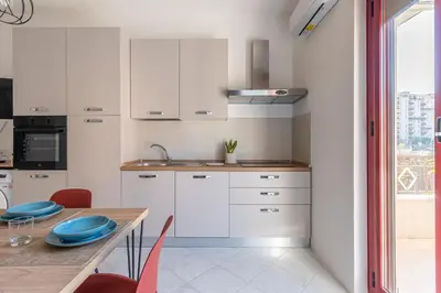 a kitchen with white cabinets and a wooden table at Ludohome in Palermo