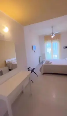 a white room with two beds and a bench at Aurea Suites in Palermo