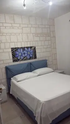 a bedroom with a bed with a blue head board at Casita Blanca in Santa Flavia