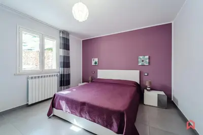 a bedroom with a purple bed and a window at Villa Privata con Piscina a Scopello in Castellammare del Golfo