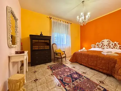 a bedroom with orange walls and a bed and a chair at O Firrìu in Carini