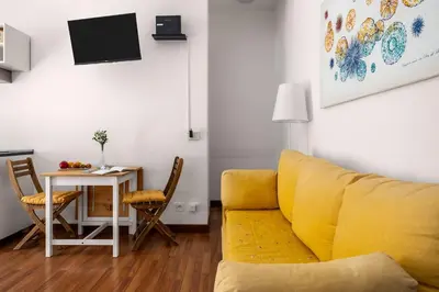 a living room with a yellow couch and a table at Sunny studio with terrace in best central area in Palermo