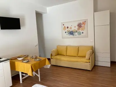 a living room with a yellow couch and a table at Sunny studio with terrace in best central area in Palermo