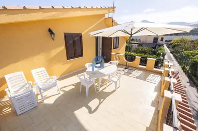 a patio with a table and chairs and an umbrella at Villa Oltremare in Lascari