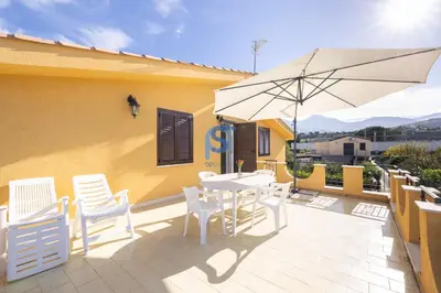 a patio with a table and chairs and an umbrella at Villa Oltremare in Lascari