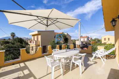 a patio with a white table and chairs and an umbrella at Villa Oltremare in Lascari