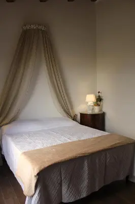 a bedroom with a bed with curtains and a table at Agriturismo Masseria Castellana in Monreale