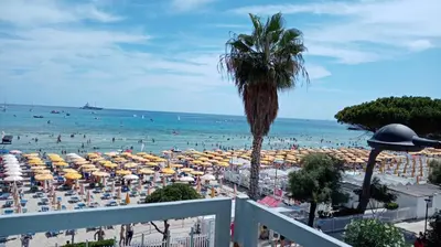 a beach with umbrellas and people in the water at Rocca Appartament Palermo Beach in Palermo
