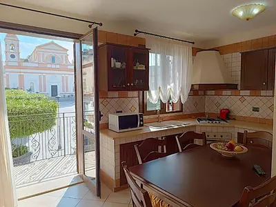 a kitchen with a table and a view of a balcony at Casa La Plaza in Balestrate