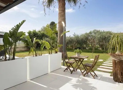 a patio with a table and chairs and a palm tree at Casa Manzella Apartments in Cinisi