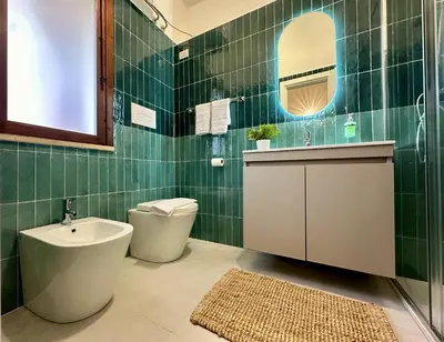 a green tiled bathroom with a toilet and a sink at Casa Manzella Apartments in Cinisi