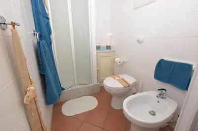 a white bathroom with a toilet and a sink at Mare Holidays in Palermo