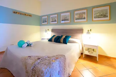 a bedroom with a large white bed with blue pillows at Mare Holidays in Palermo