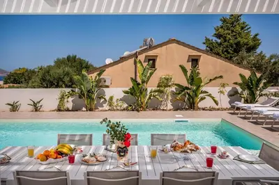 a table with food on it next to a swimming pool at Rosvì Villa in Castellammare del Golfo