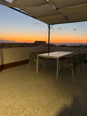 a table and chairs on a roof with the sunset at Casa Lo Bianco in Terrasini