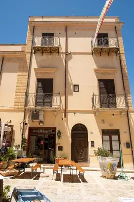 a building with tables and benches in front of it at GaR07 in Castellammare del Golfo