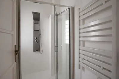 a glass shower door in a white bathroom at La Lumia Apartment in Palermo