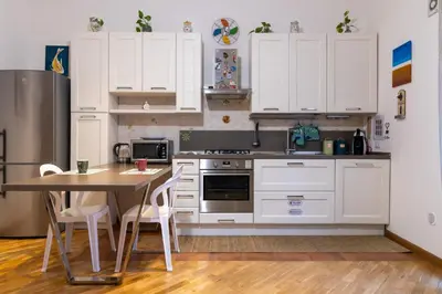 a kitchen with white cabinets and a table with chairs at GuestHost - Al Cassaro Holiday Home in Palermo
