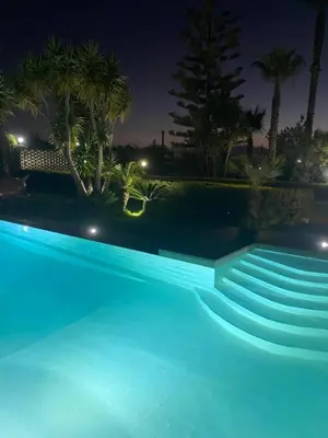 a blue swimming pool at night with palm trees at Villa Oasi della Pace based in Partinico in Partinico