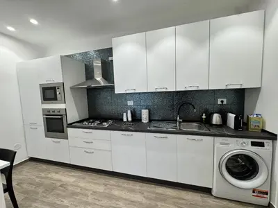 a kitchen with white cabinets and a washing machine at Al Grande Pino - Private pool, Jacuzzi and amazing Sunset in Campofelice di Roccella
