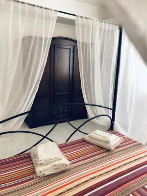 a bed with white curtains and two towels on it at Attico Giusy in Balestrate