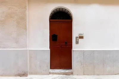 a red door in a white building with an arch at Meschita Little House in Palermo
