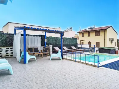 a patio with a blue canopy and chairs and a pool at Villa Blu Corallo by Interhome in Alcamo Marina