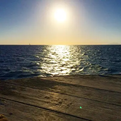 a sun setting over the ocean on a wooden pier at Villa Castelforte, con piscina a Mondello in Palermo