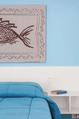 a bedroom with a blue bed and a picture on the wall at Cala & Cassari View By DomuSicily in Palermo