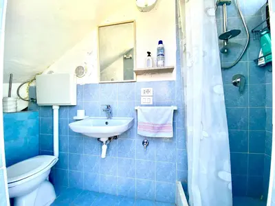 a blue tiled bathroom with a sink and a toilet at Villa dei Gerani, a 500 mt dal mare in Alcamo