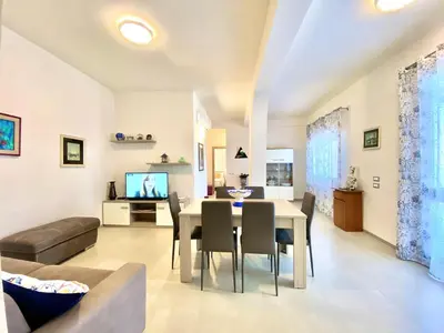 a dining room and living room with a table and chairs at Villa dei Gerani, a 500 mt dal mare in Alcamo