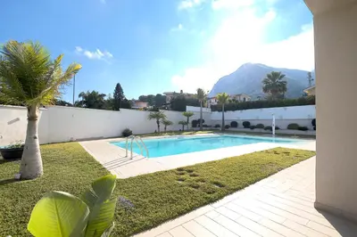 a swimming pool with a palm tree next to a building at Private Villa, Sun & Pool in Mandra Capreria