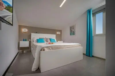 a bedroom with a large white bed with blue pillows at Villa Sikelia con fantastica piscina in Alcamo
