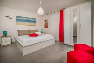 a bedroom with a white bed with red pillows at Villa Sikelia con fantastica piscina in Alcamo
