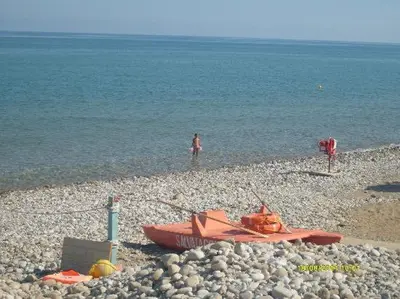 a boat on a rocky beach next to the water at Sweet Summer House in Campofelice di Roccella