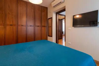 a bedroom with a blue bed and a flat screen tv at GuestHost - Casa Giacomo in central Palermo in Palermo