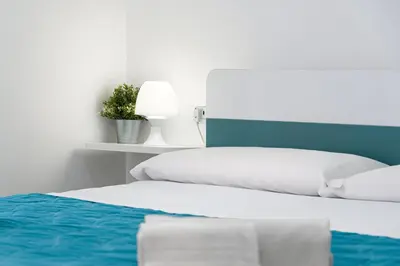 two beds with white sheets and a blue headboard at Panarea SVLC in San Vito lo Capo