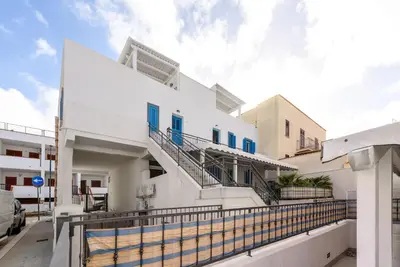 a white house with blue windows and a balcony at Panarea SVLC in San Vito lo Capo