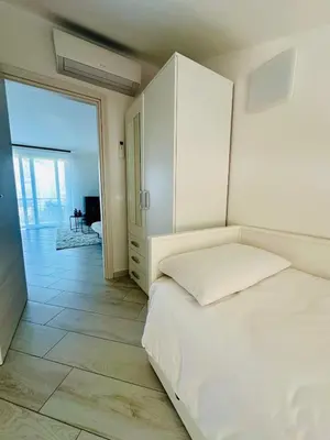 a bedroom with a white bed and a sliding glass door at Comfy Holiday House in Castellammare del Golfo