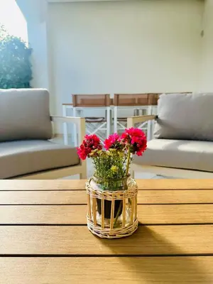 a vase with red flowers sitting on a table at Comfy Holiday House in Castellammare del Golfo