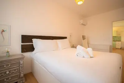 a bedroom with a large white bed and a dresser at Solemar Sicilia - Casa Alba in Santa Flavia