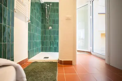 a bathroom with a shower with a green tile wall at Solemar Sicilia - Casa Alba in Santa Flavia