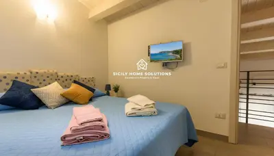 a bedroom with a blue bed with towels on it at Charming Loft near the Sea - Castellammare del Golfo by Sicily Home Solutions in Castellammare del Golfo