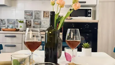a table with two glasses of wine and a vase with flowers at Charming Loft near the Sea - Castellammare del Golfo by Sicily Home Solutions in Castellammare del Golfo