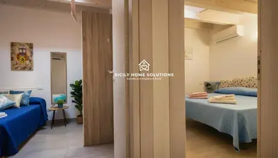 a room with two beds and a door to a bedroom at Charming Loft near the Sea - Castellammare del Golfo by Sicily Home Solutions in Castellammare del Golfo
