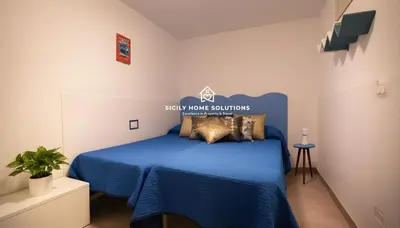 a bedroom with a bed with blue sheets and pillows at Charming Loft near the Sea - Castellammare del Golfo by Sicily Home Solutions in Castellammare del Golfo