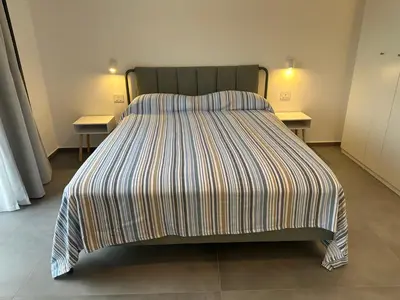 a bed with a striped comforter in a room at Villa Muntaja in Scopello