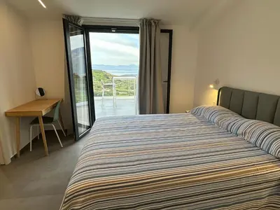 a bedroom with a bed and a door to a balcony at Villa Muntaja in Scopello