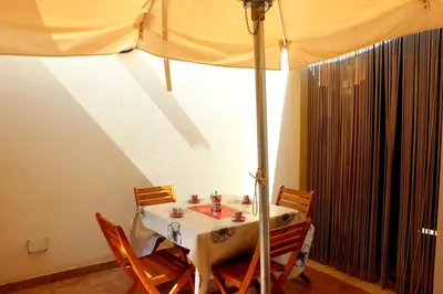 a table with chairs and an umbrella in a room at Appartamento Calvino piano terra in via Mulino 31 in San Vito lo Capo